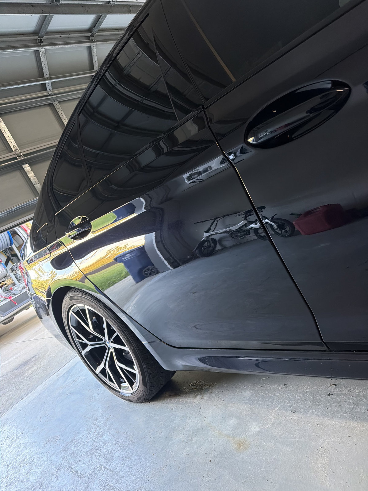 Close-up of a black BMW 5 Series, showing its rear wheel and glossy bodywork
