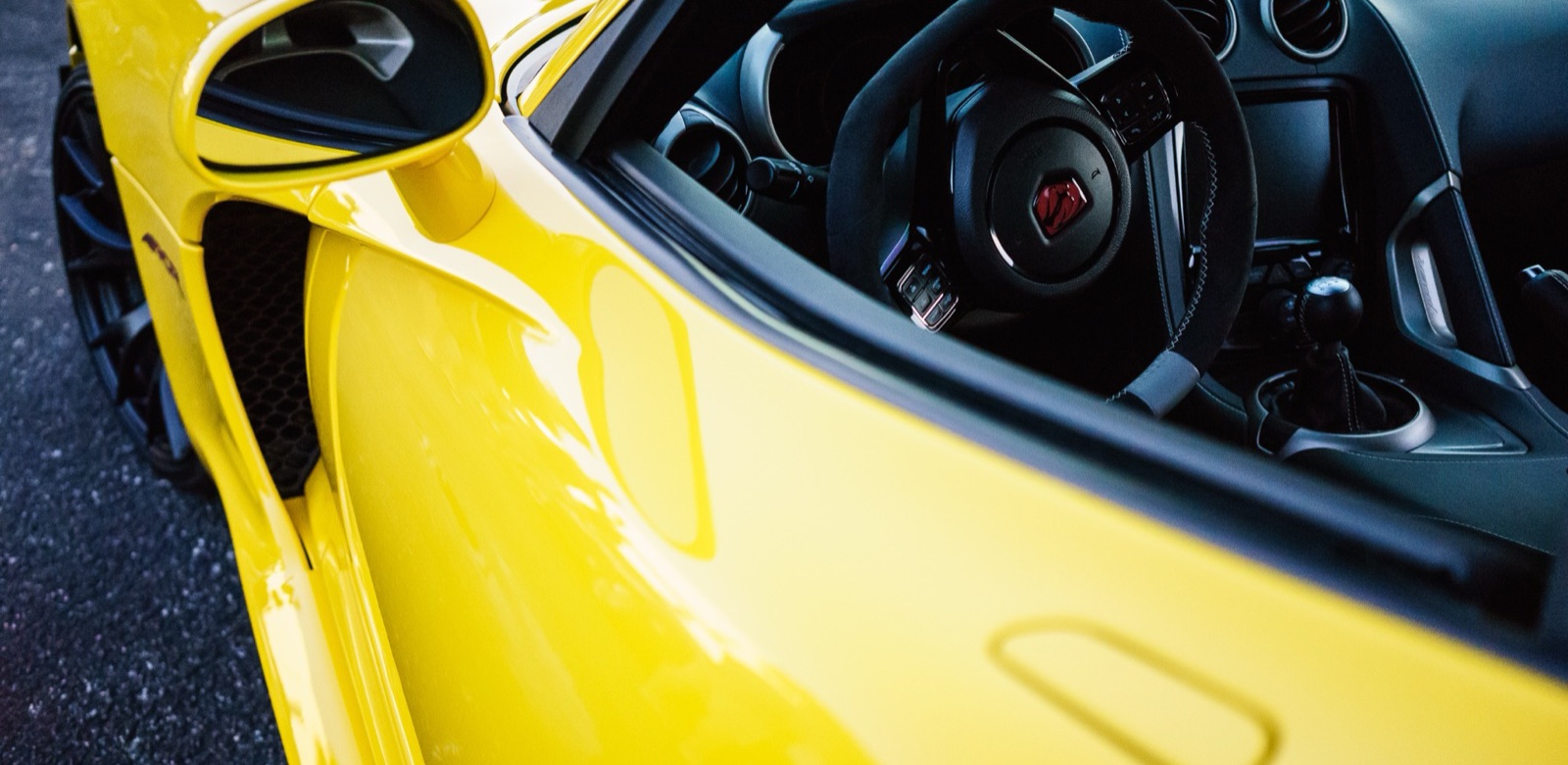 Close-up of a yellow sports car’s mirror, door and cockpit